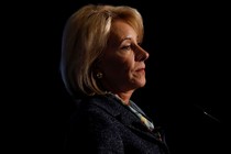 Betsy DeVos speaking at podium against a black background