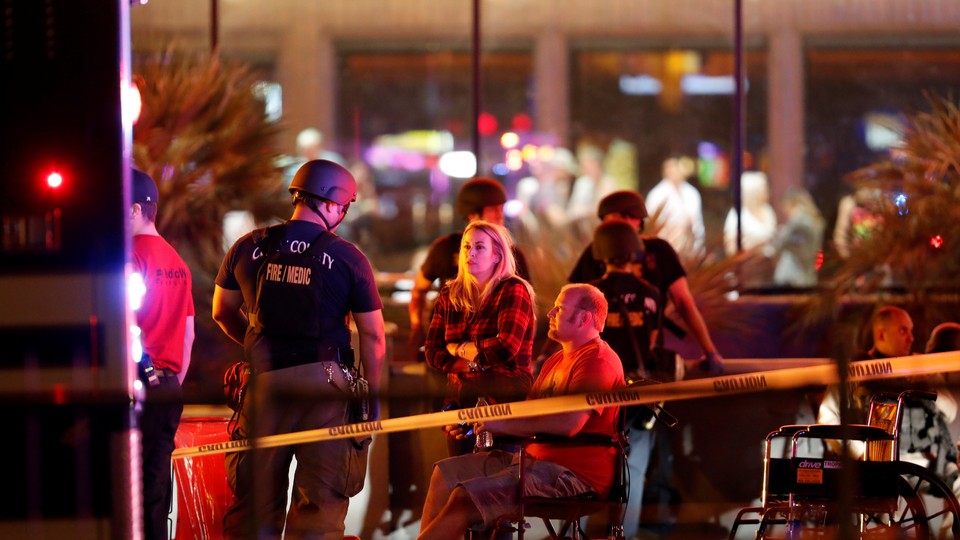 People wait in a medical staging area next to an ambulance.