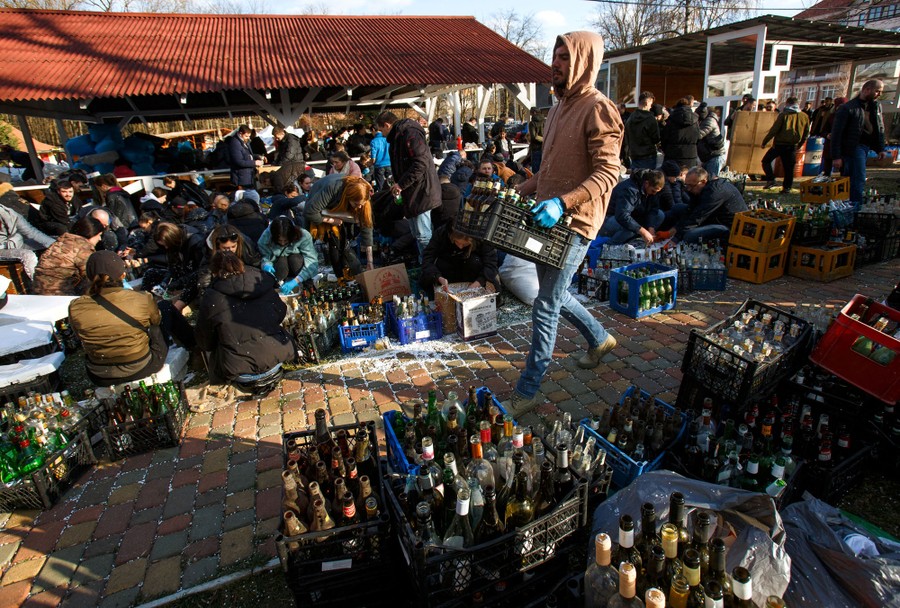 A person carries a crate of bottles among many others preparing hundreds of bottles to be used as Molotov cocktails.