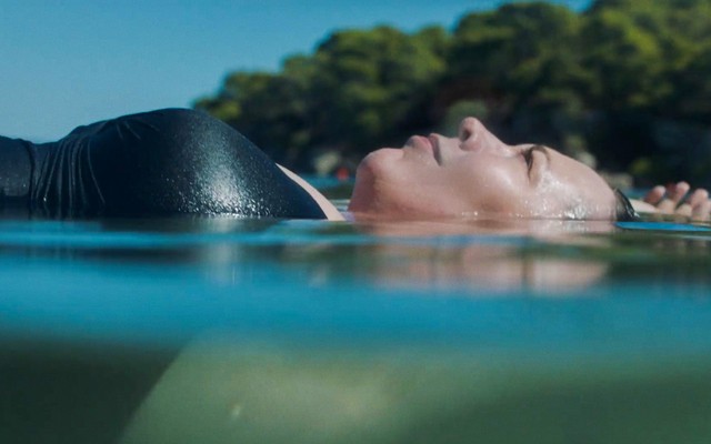 Olivia Colman lying on her back half submerged in the ocean