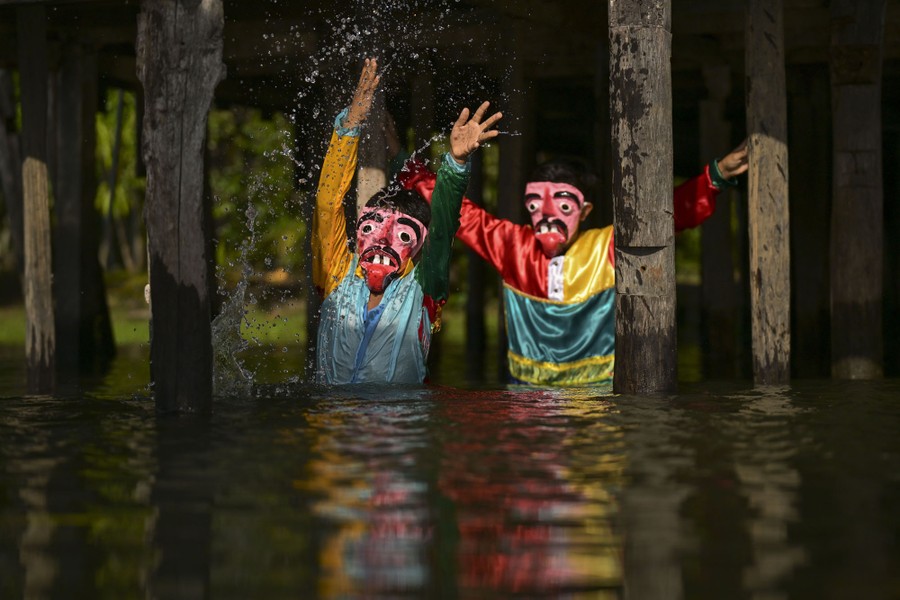 Two people wear masks and colorful shirts while standing waist-deep in water.