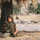 An American sits under a palm tree as his comrades inspect the damage from the suicide bombing that destroyed a Marine barracks in Beirut, Lebanon, in 1983.