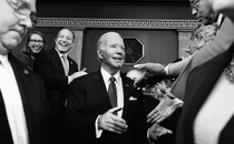 A black-and-white photo of Joe Biden shaking hands with members of Congress