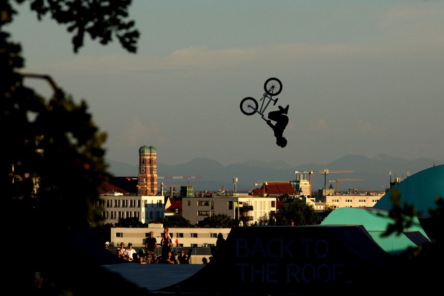 A BMX rider in mid-jump, against a backdrop of the Munich skyline