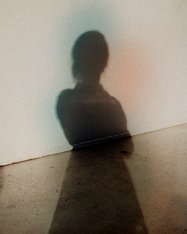 The shadow of a woman against a blank wall