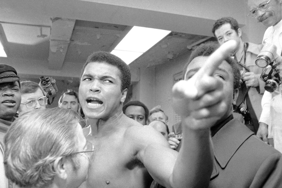 Muhammad Ali points, animated, as others crowd around him.
