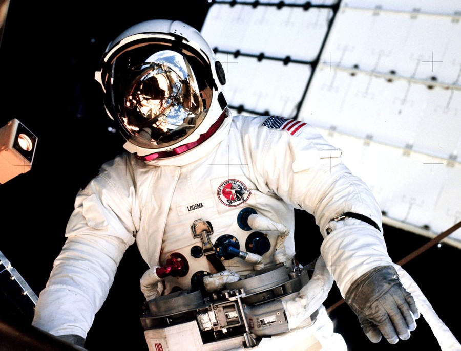 An astronaut wearing a spacesuit is pictured outside of a spacecraft.