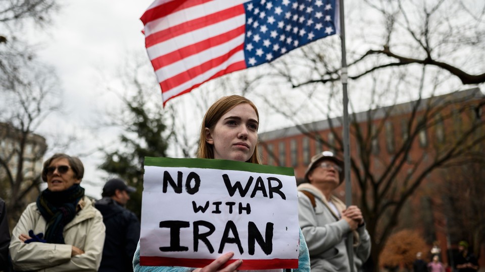 A protester holds a sign reading "No war with Iran."