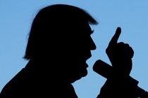 A silhouette of Donald Trump talking into a microphone with his finger pointing to the sky.