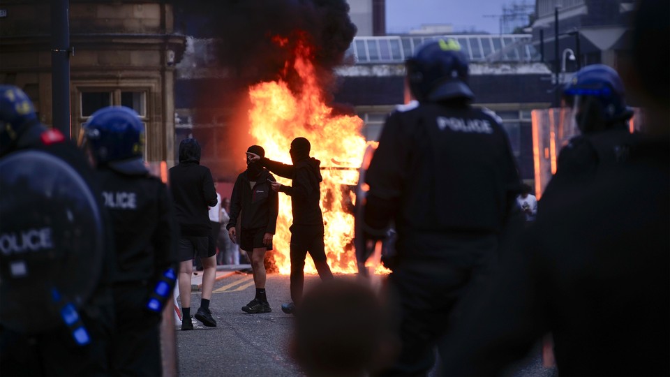 Rioters face off with police in front of a burning car in Sunderland, United Kingdom