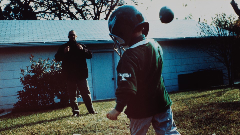 A father and son play football.