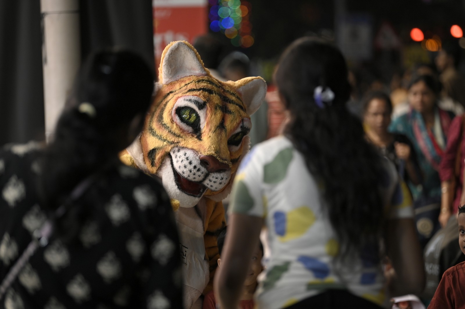 A man dressed as a tiger stands in front of a showroom, greeting people.