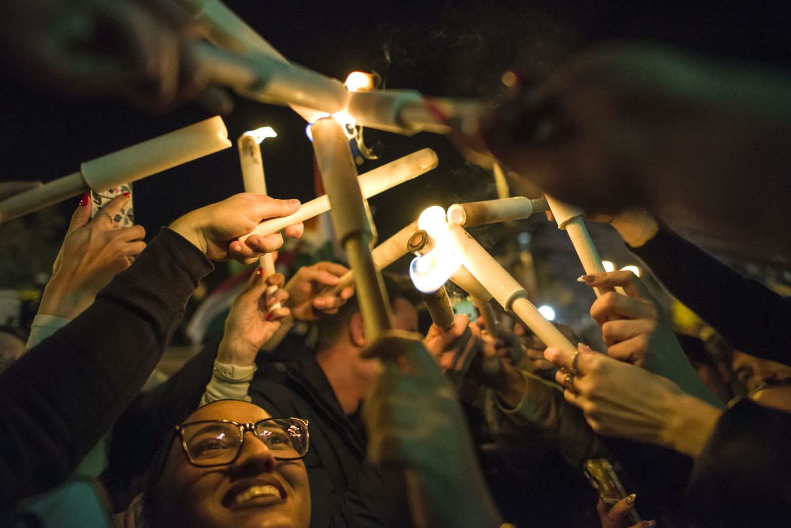 People hold up glowing torches and light tubes during an election night rally.