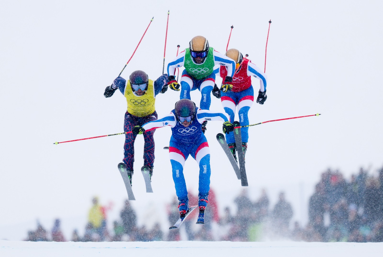 Four ski racers, seen in midair, jumping during a race