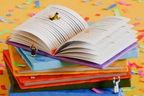 Small figurines and confetti surround a pile of books.