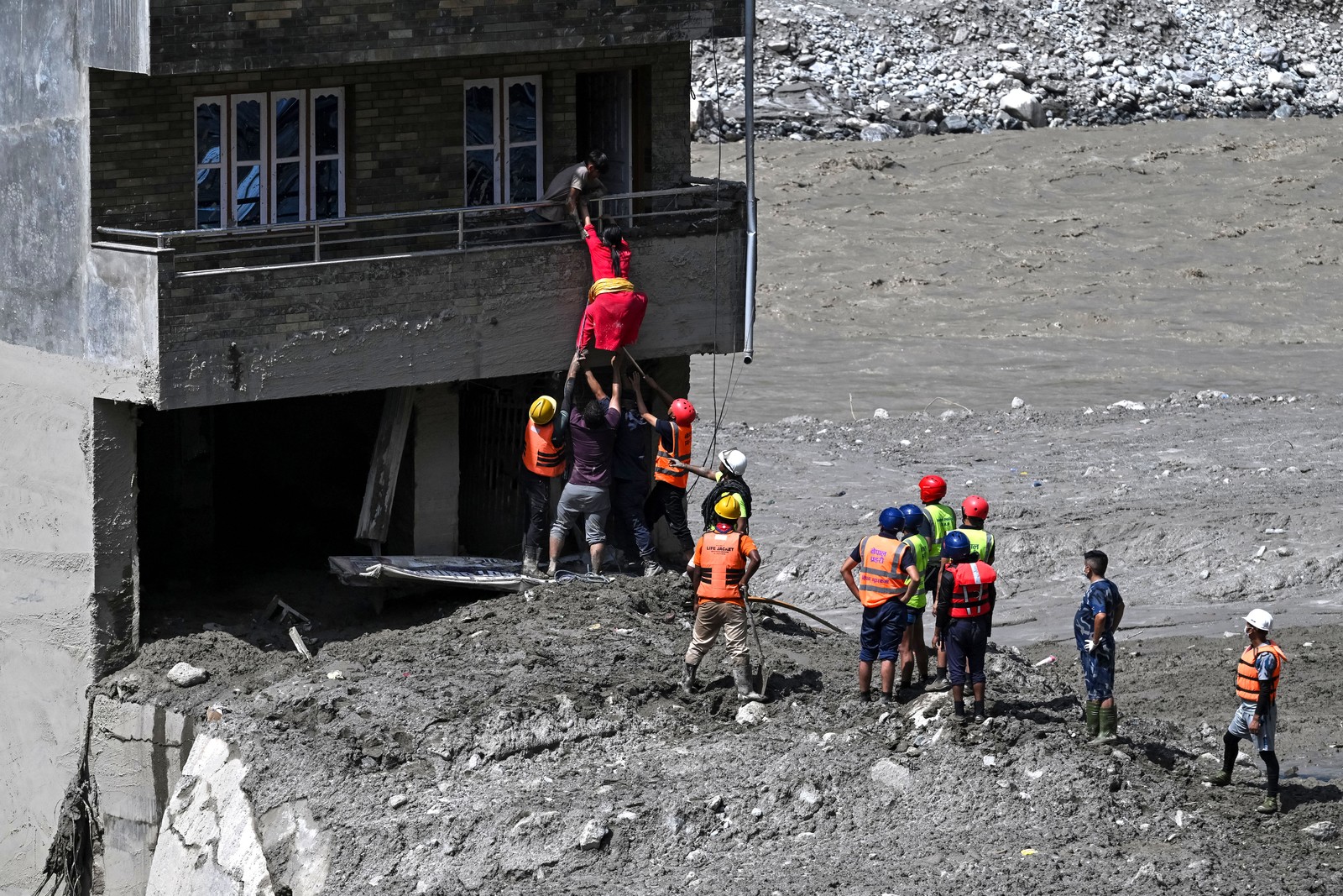 Police personnel rescue stranded residents from a flood-damaged house.