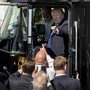 President Donald Trump points to a crowd of men from the driver's seat of a large truck on the south lawn of the White House