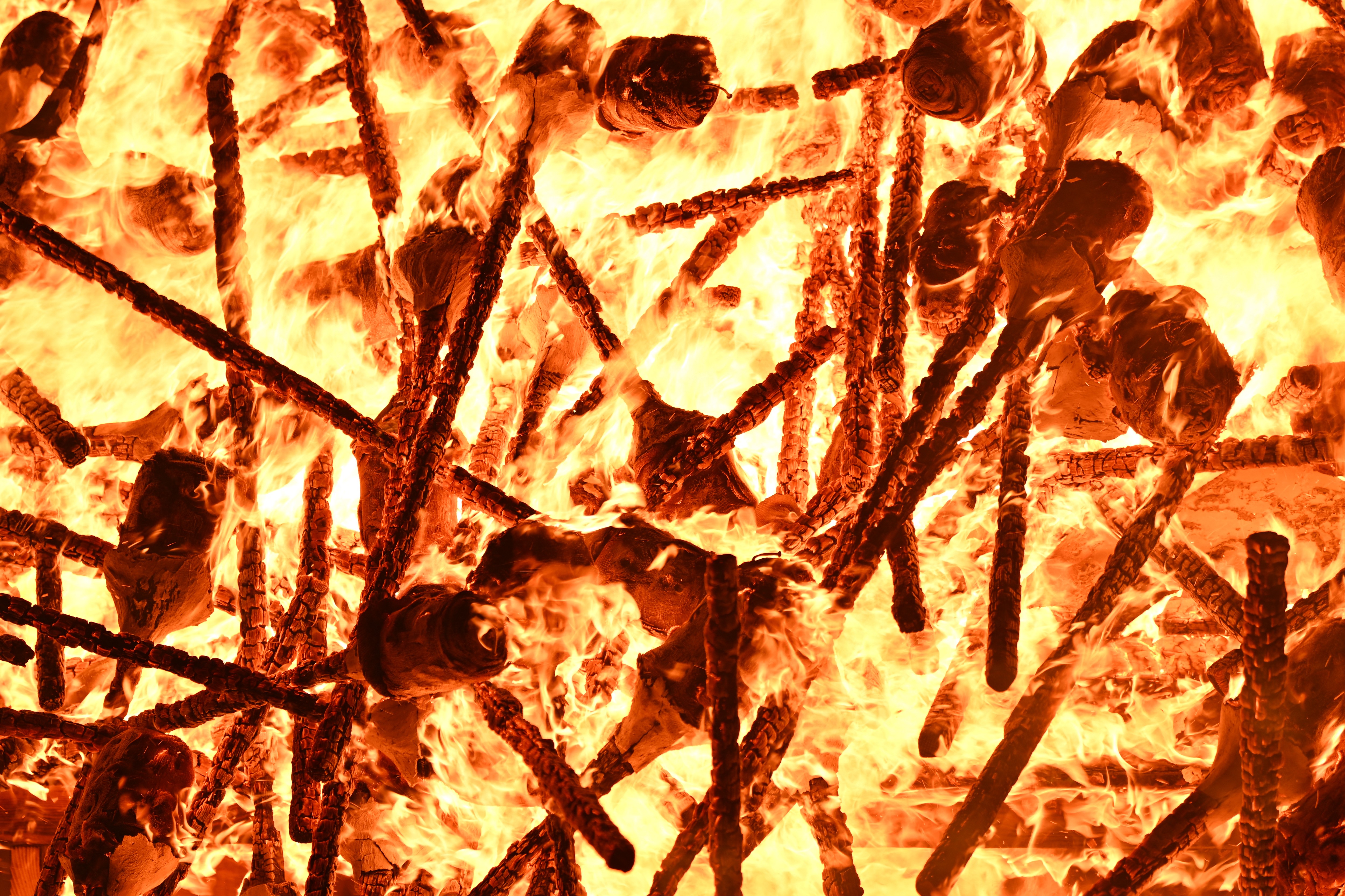 A close view of dozens of burning torches that have been tossed into a pile.