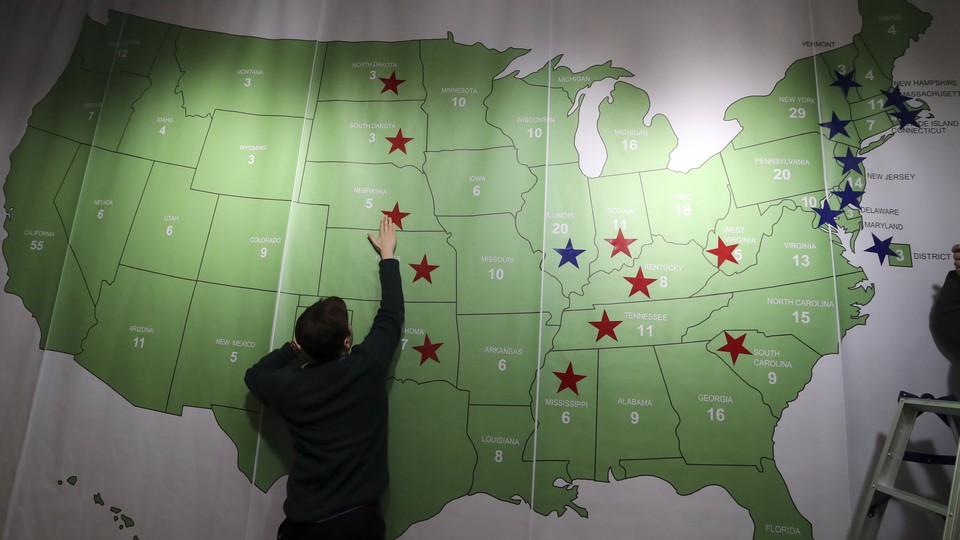 A man reaches up to touch a map of the United States decorated with red and blue stars.
