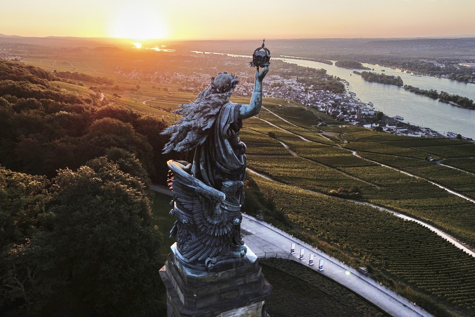 An aerial view of a tall statue standing above vineyards