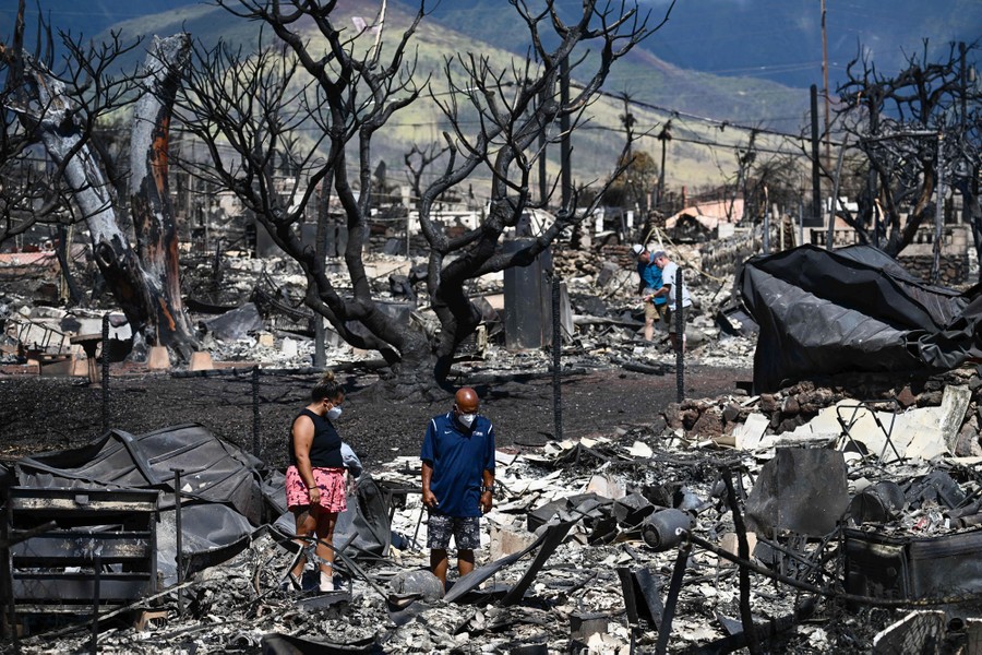 People pick through ashes and rubble in a burned neighborhood.