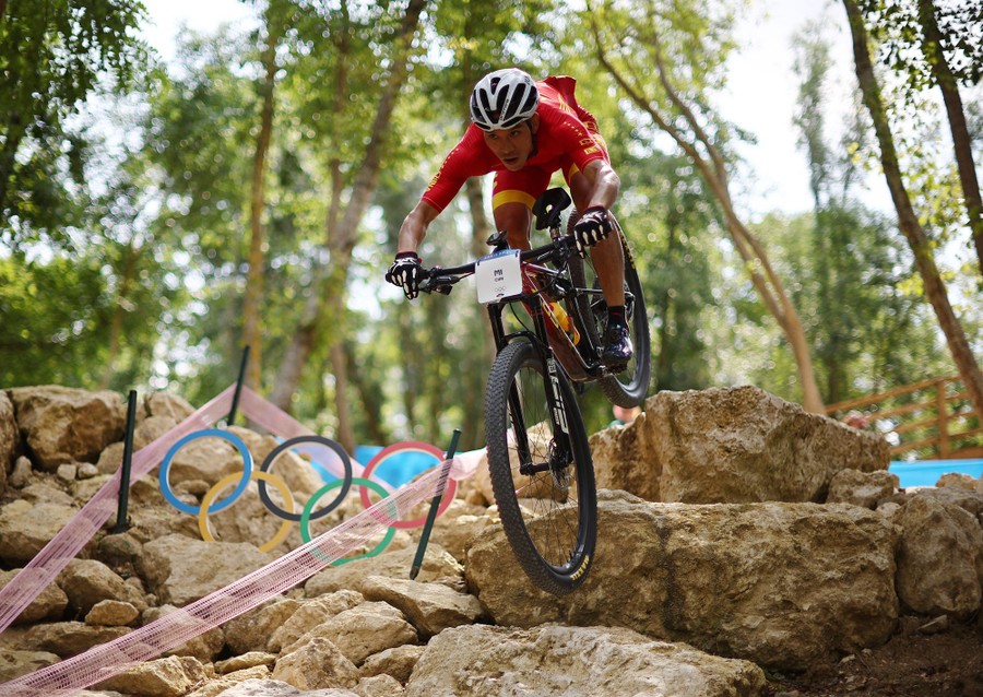 An athlete on a mountain bike traverses a path through boulders.