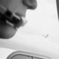 A black-and-white photo of a pilot in a small aircraft, with another plane viewed in the near distance.
