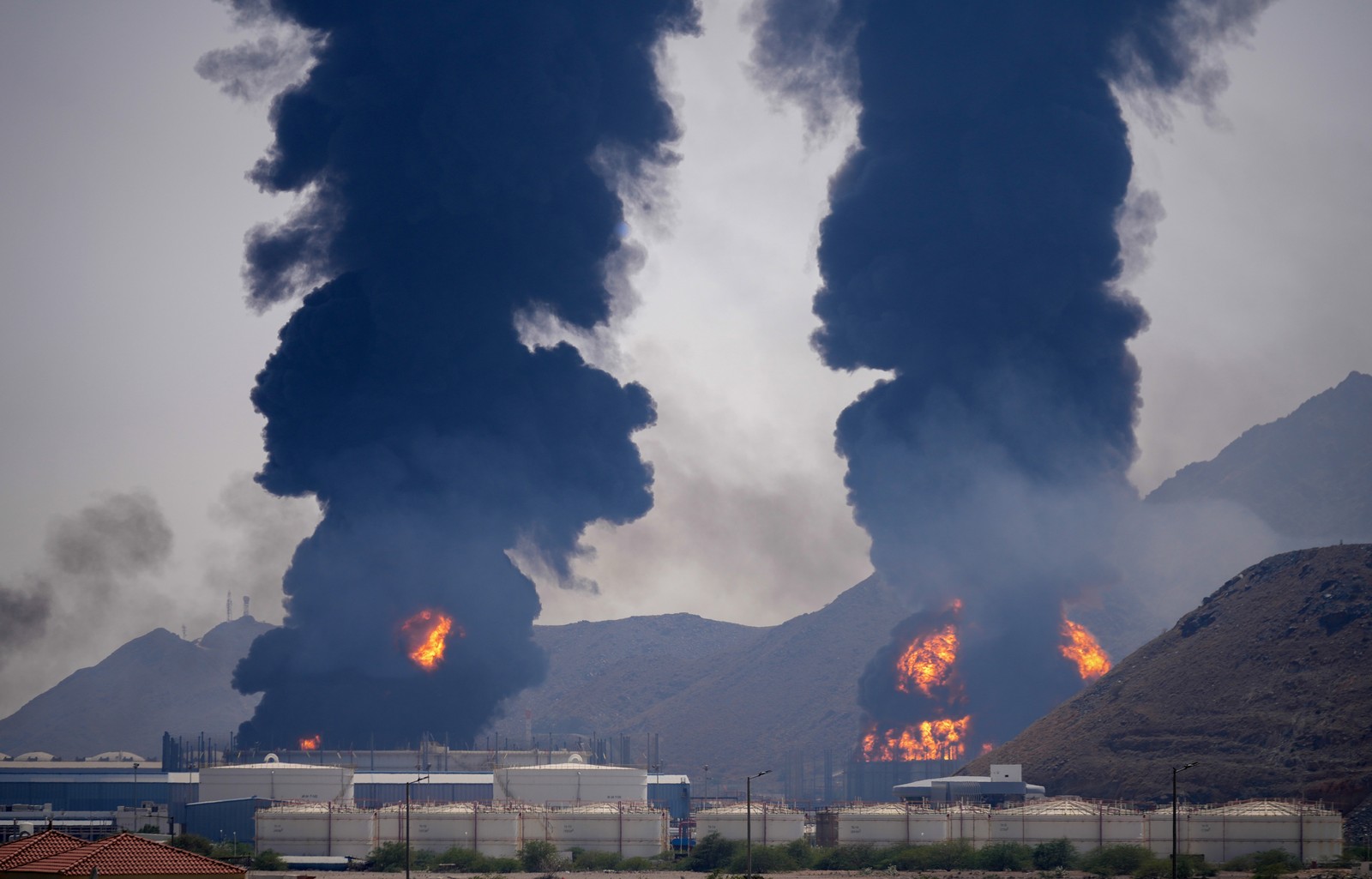 Two columns of of smoke and fire rise after debris from an intercepted Iranian drone struck an oil facility.