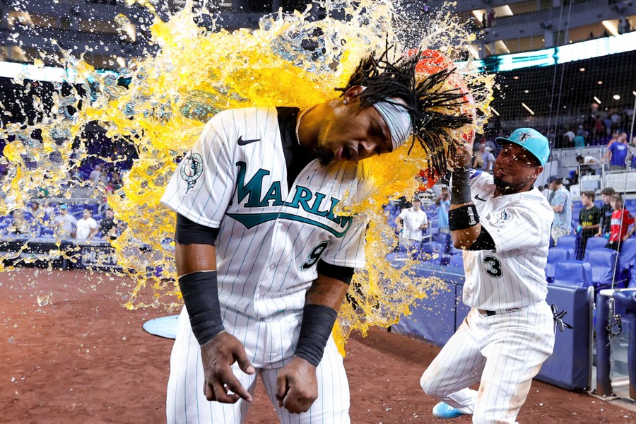 A baseball player dumps a tub of gatorade onto a teammate.