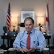Framed by the U.S. and Alabama state flags, Doug Jones sits in an office.