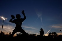 A silhouette of a high-school football player throwing a pass