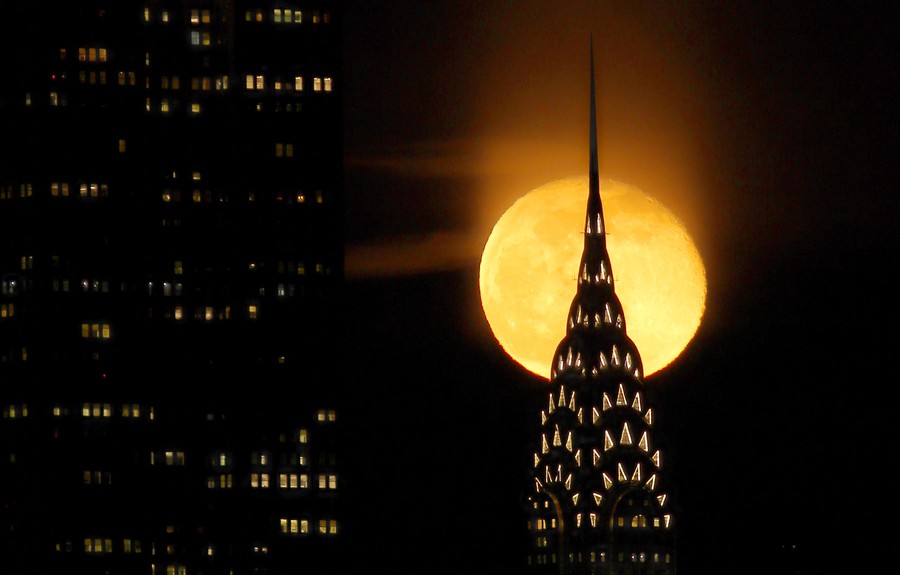 A nearly full moon rises behind the Chrysler Building in New York City.