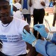 A person wearing blue gloves administers a vaccine to a man wearing a white shirt