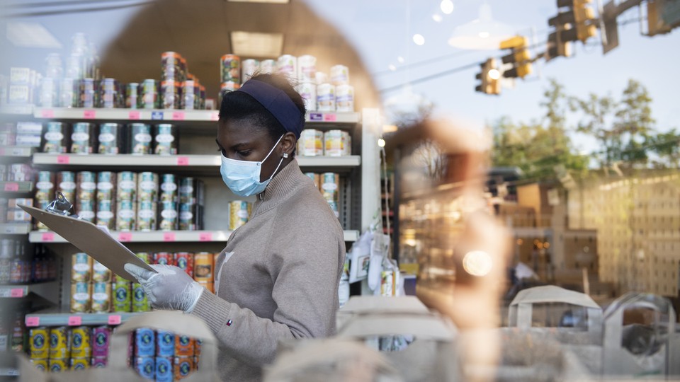 A cashier wearing a face mask, looking at a clipboard in a store