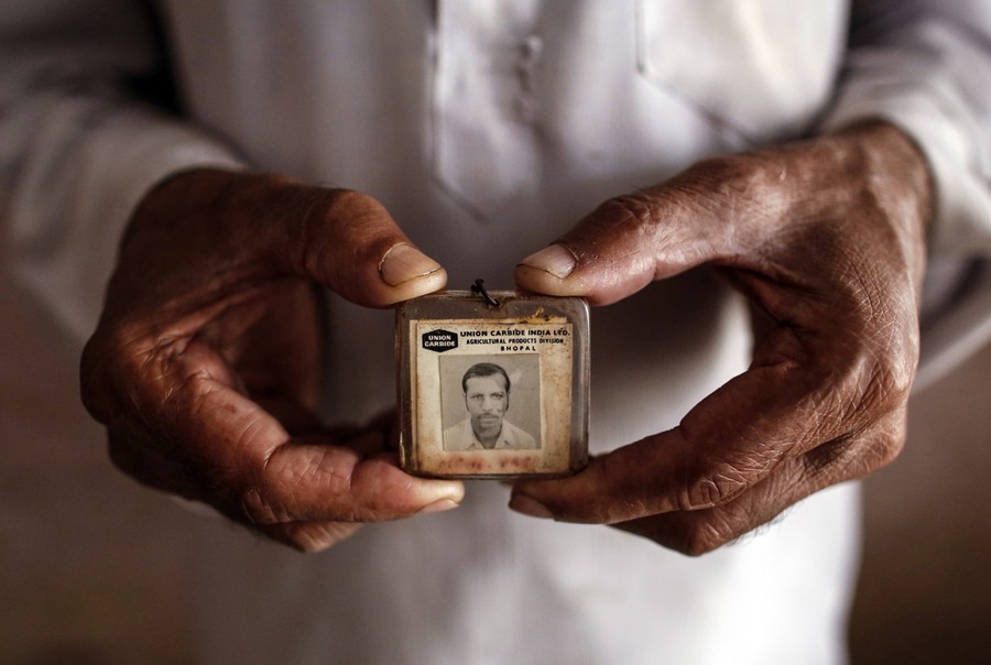 A close-up of two hangs holding a faded ID card.