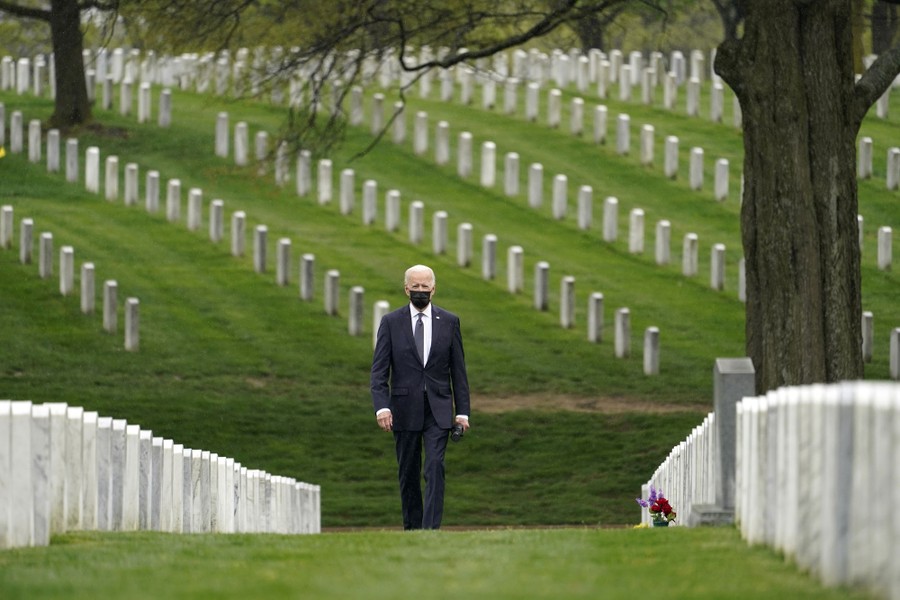 President Joe Biden walks alone through a military cemetery.