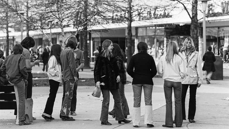 black and white photo of young people hanging out outside stores