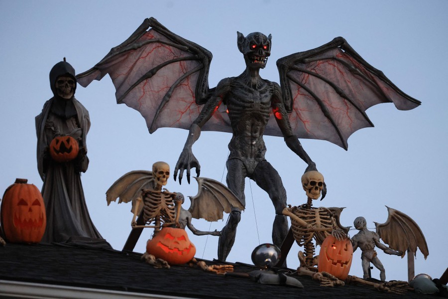 Plastic ghouls and goblins line a roof as Halloween decorations.