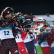 Biathletes stand side by side, rifles raised, during a shooting bout.