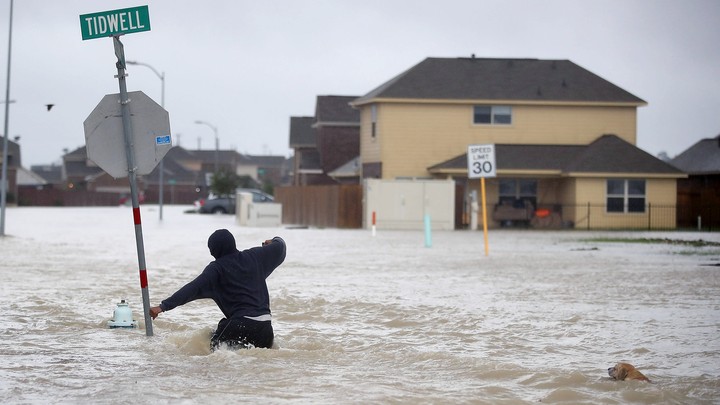A person wades through high floodwaters.