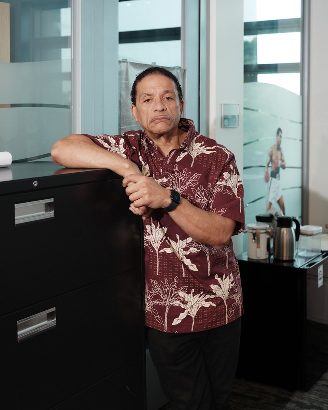 A man in a Hawaiian shirt leans against a filing cabinet