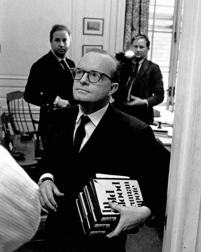 Black-and-white photo of Truman Capote holding copies of his book