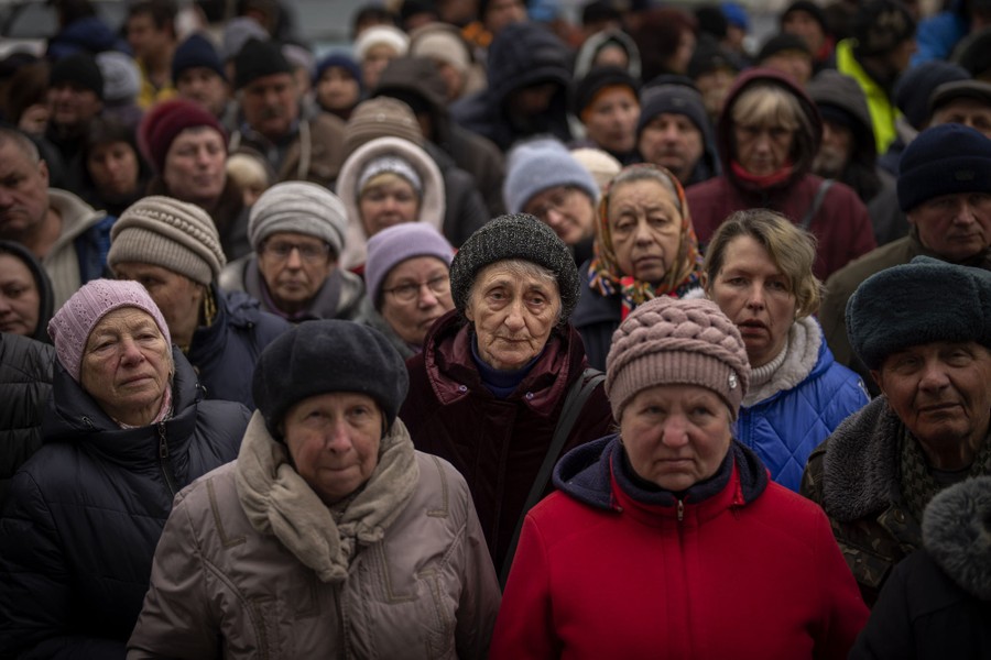 A crowd of mostly older women stands outside, waiting for food.
