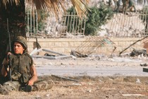 An American sits under a palm tree as his comrades inspect the damage from the suicide bombing that destroyed a Marine barracks in Beirut, Lebanon, in 1983.