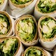 A photo of paper-covered wraps, cut from the top so you can see lettuce and chicken
