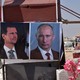 Flowers lie next to posters of Assad and Putin in Idlib.