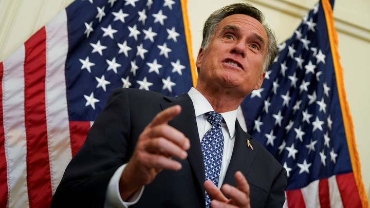 Mitt Romney stands in front of two American flags.