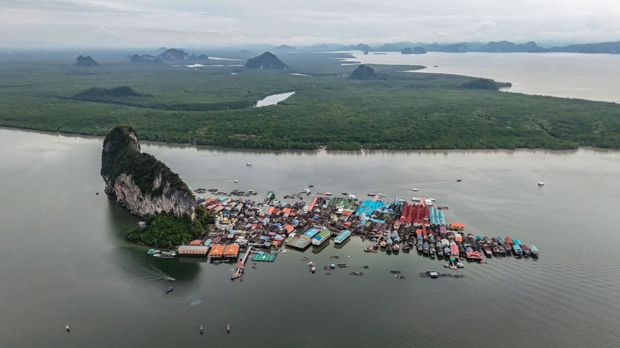 An aerial view of a floating fishing village built alongside a small rocky island