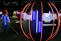 A person cleans up in a room full of computers and neon lights.