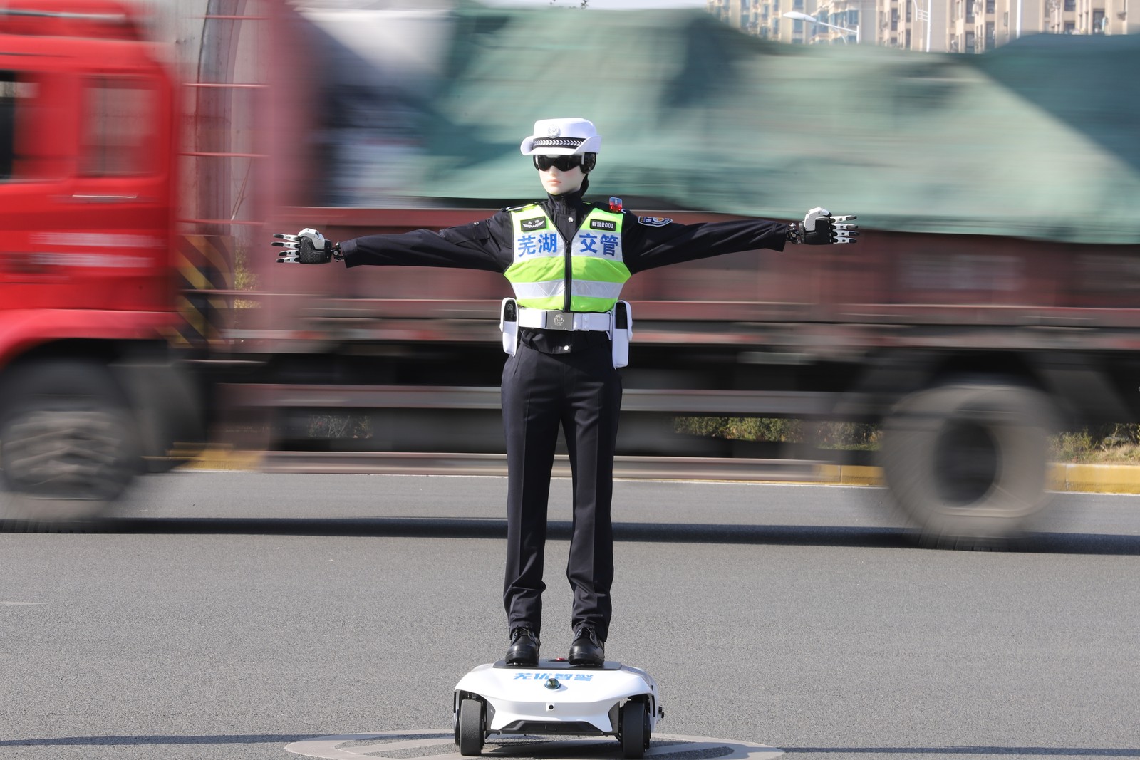 A humanoid robot dressed in a traffic police uniform stands with arms outstretched in a road.